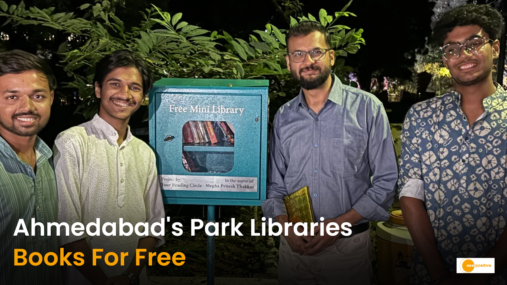 A wooden mini library box installed in a green public park with books visible through transparent doors.